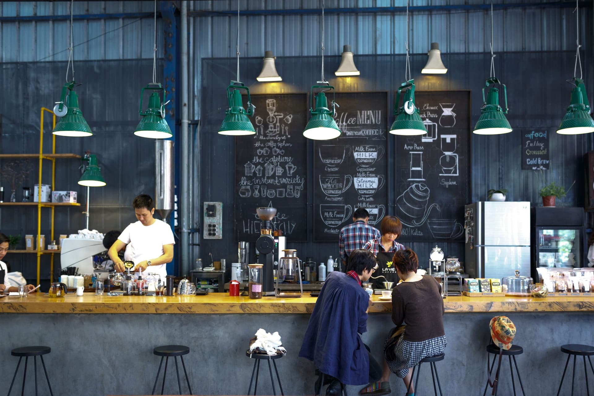 Comedor de restaurante vacío durante una remodelación, con mesas y cocina a la vista