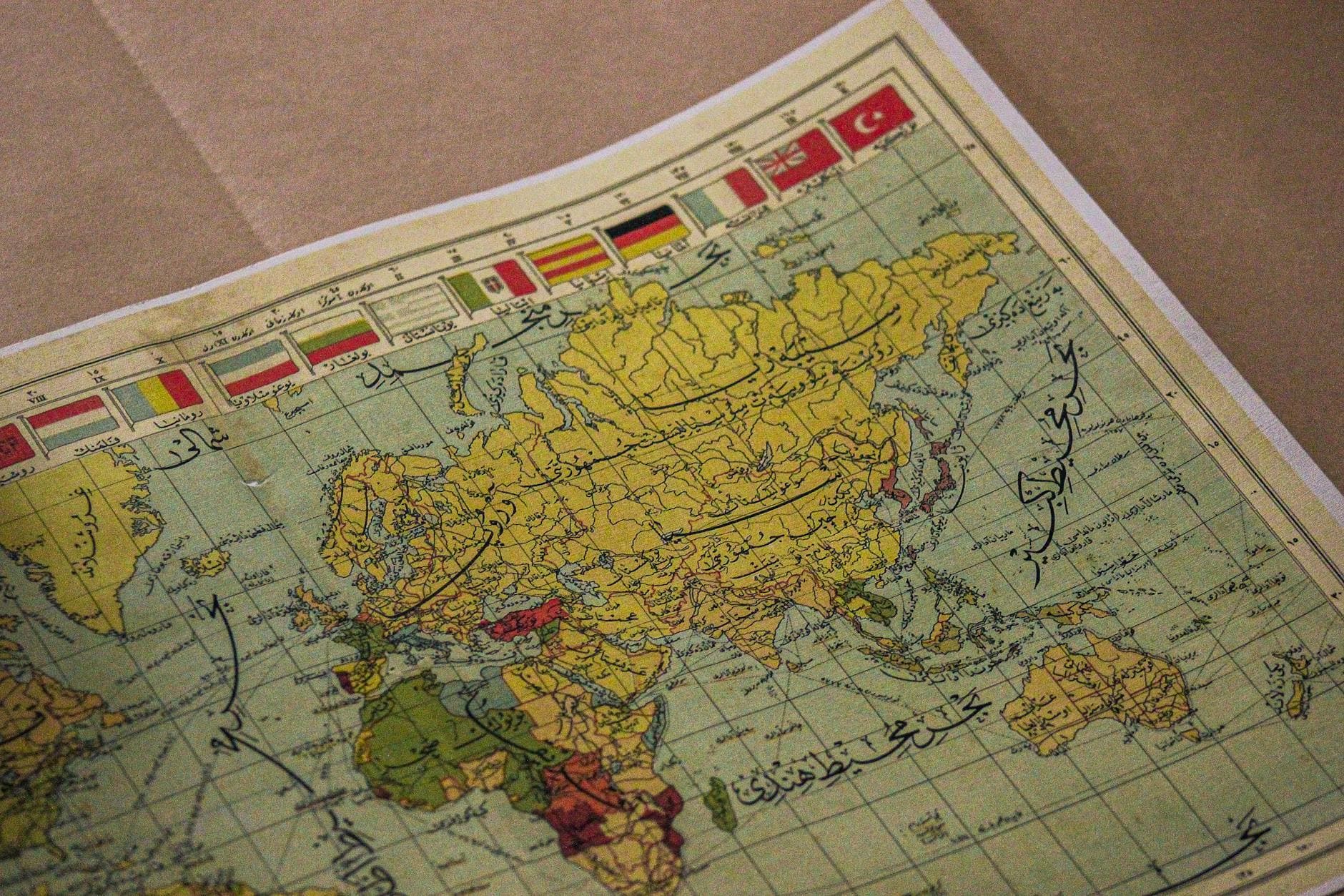 Antique world map showing continents, Arabic script, and various national flags.