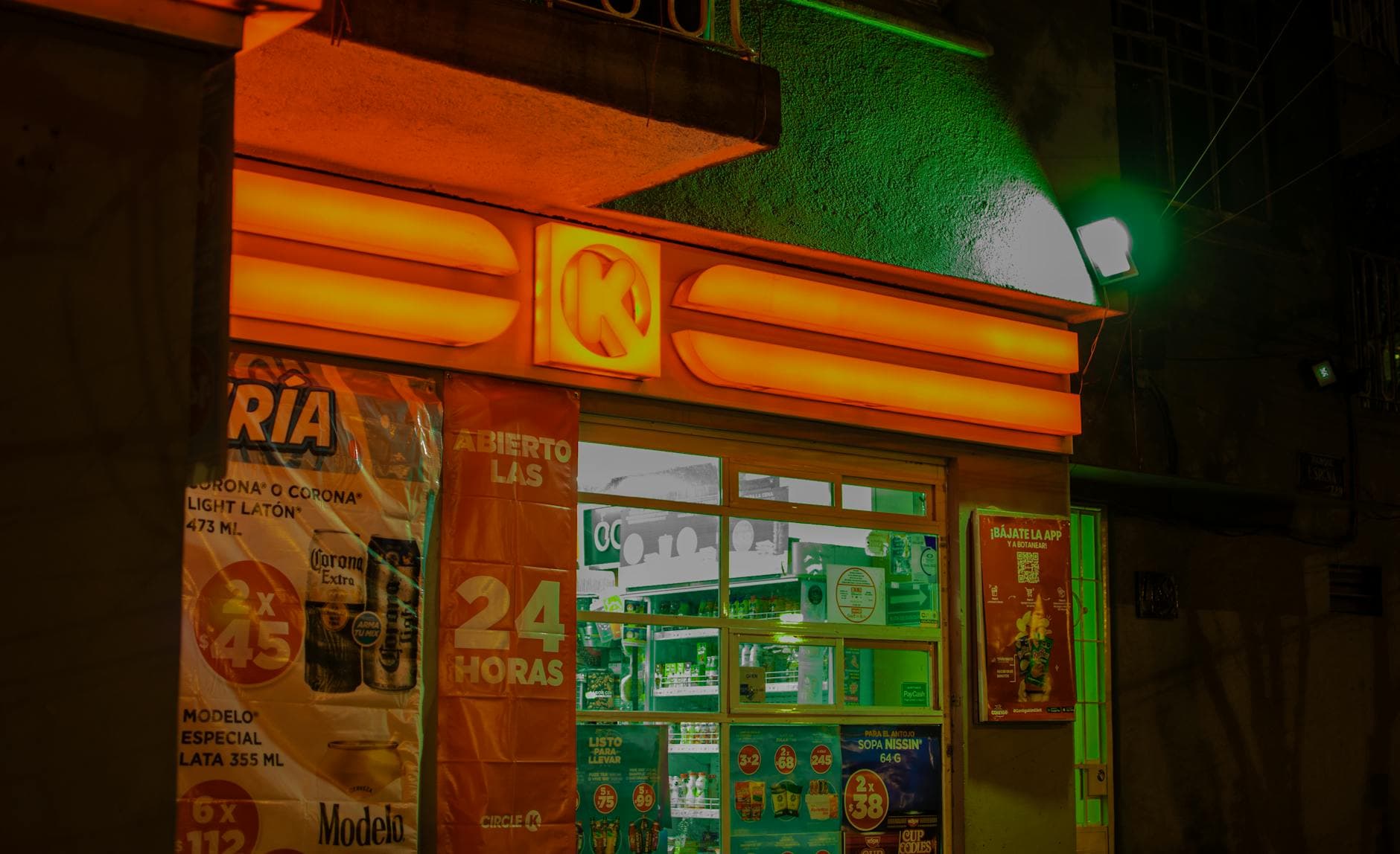 A brightly illuminated convenience store with neon lights at night, showcasing vibrant colors and signage.